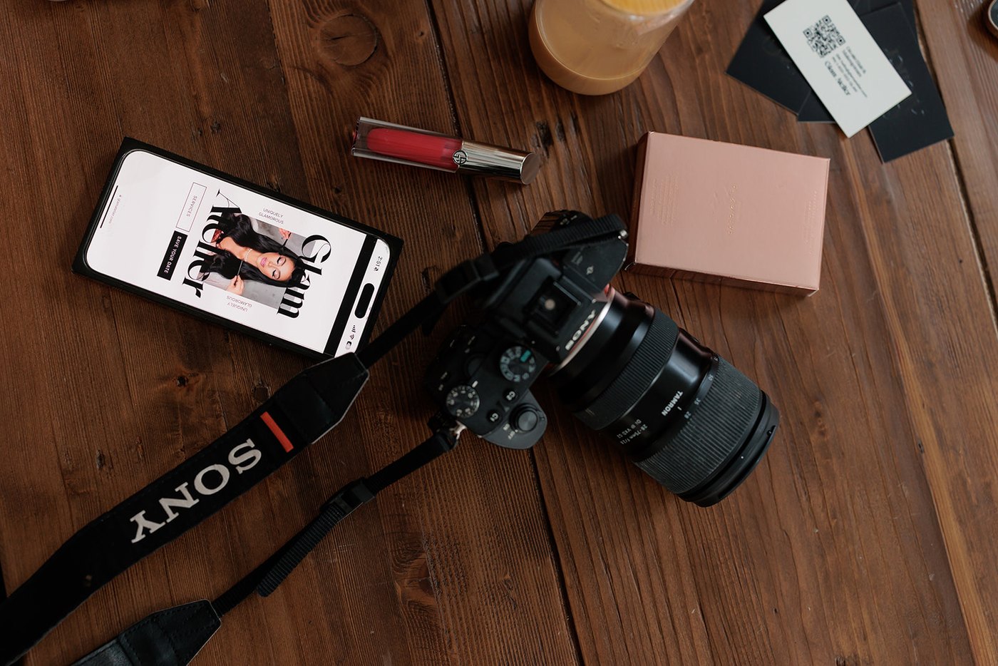 The Glam Atelier site open on a phone beside a camera